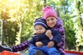 Two cute adorable playful caucasian siblings boy girl child enjoy havefun on playground at backyard or city park