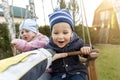 Two cute adorable playful caucasian siblings boy girl child enjoy having fun swinging wooden swing at backyard together Royalty Free Stock Photo