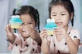 Two cute asian child girls having fun to eat blue cupcake