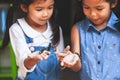 Two cute asian child girls holding black caterpillar