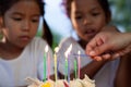 Two asian child girls lighting candle on birthday cake together in birthday party Royalty Free Stock Photo