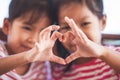 Two cute asian child girls making heart shape with hands together