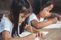 Two cute asian child girls reading a book and writing a notebook in the classroom Royalty Free Stock Photo