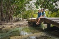 Two cute asian child girls sitting on the wooden bridge over the river and enjoy with nature together