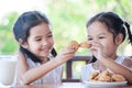 Two cute asian little child girls are eating cookies with milk Royalty Free Stock Photo