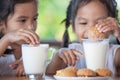 Two cute asian little child girls are eating cookies with milk Royalty Free Stock Photo