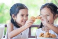 Two cute asian little child girls are eating cookies with milk Royalty Free Stock Photo