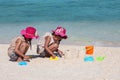 Two asian little child girls sitting and playing with sand together on the beach near the beautiful sea in summer vacation Royalty Free Stock Photo