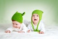 Two cute babies lying in frog hats on spft blanket