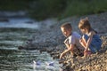 Two cute blond children, boy and girl on river bank sending in w Royalty Free Stock Photo