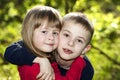 Two cute blond funny happy smiling children siblings, young boy brother embracing sister girl outdoors on bright sunny green bokeh Royalty Free Stock Photo