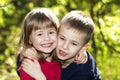 Two cute blond funny happy smiling children siblings, young boy brother embracing sister girl outdoors on bright sunny green bokeh Royalty Free Stock Photo