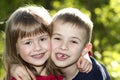 Two cute blond funny happy smiling children siblings, young boy brother embracing sister girl outdoors on bright sunny green bokeh Royalty Free Stock Photo