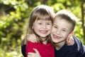 Two cute blond funny happy smiling children siblings, young boy brother embracing sister girl outdoors on bright sunny green bokeh Royalty Free Stock Photo