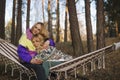 Two cute blonde women sitting in the hammock and hugging with trust and support