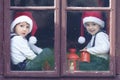 Two cute boys, looking through a window, waiting for Santa