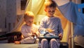 Two cute boys in pajamas playing games on tablet computer in bed at night. Children with gadgets, education, kids development Royalty Free Stock Photo