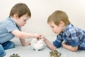 Two cute boys, preschoolers, put coins in the piggy Bank. Children learn to save their savings. Brothers save money for their Royalty Free Stock Photo