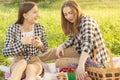 Two cute Caucasian girls in a Park in nature in summer on a Sunny day on a picnic have fun, laugh, eat, communicate, talk Royalty Free Stock Photo