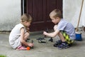 Two cute children blond pretty preschool girl and handsome boy playing outdoors with plastic toys on warm summer day on background Royalty Free Stock Photo