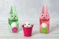 Two cute Easter bunny egg holders and an egg with a face in a bucket. Easter concept. Rabbits are made in origami technique Royalty Free Stock Photo