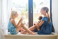 Two cute european toddler girls playing near window at home