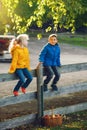 Two cute funny Caucasian children boy girl sitting on wooden rustic fence in park farm outside Royalty Free Stock Photo