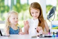 Two cute funny sisters applying make-up on sunny summer day at home Royalty Free Stock Photo