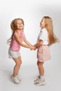 Two girlfriends are jumping holding hands. Bright portrait