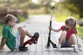 Two cute happy funny laughing young children, brother and sister, having fun on sunny pavement, handsome boy with skateboard and Royalty Free Stock Photo