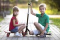 Two cute happy funny smiling young children, brother and sister, posing for camera, handsome boy with scooter and pretty long- Royalty Free Stock Photo