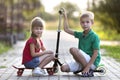 Two cute happy funny smiling young children, brother and sister, posing for camera, handsome boy with scooter and pretty long- Royalty Free Stock Photo