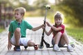 Two cute happy funny smiling young children, brother and sister, posing for camera, handsome boy with scooter and pretty long- Royalty Free Stock Photo