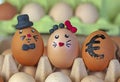 two cute hare eggs in a black hat and with a red plasticine bow in an egg container with a painted euro on the egg. Rise in price