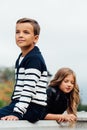 Two cute kids are sitting on the railing. Marble-stone fountain. Royalty Free Stock Photo