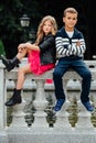 Two cute kids are sitting on the railing. Marble-stone fountain. Royalty Free Stock Photo