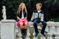 Two cute kids are sitting on the railing. Marble-stone fountain. Royalty Free Stock Photo