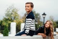 Two cute kids are sitting on the railing. Marble-stone fountain. Royalty Free Stock Photo