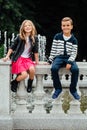 Two cute kids are sitting on the railing. Marble-stone fountain. Royalty Free Stock Photo