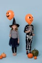 Two cute kids in witch and skeleton costumes holding orange halloween balloons Royalty Free Stock Photo