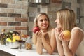 Two cute lesbian women drink red wine in the kitchen and have a nice chat