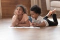 Two cute african kids playing drawing together on warm floor Royalty Free Stock Photo