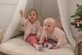 Two cute little baby girls play in a spacious bright minimalistic children`s room.