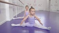 Two cute little ballerinas girls stretching at ballet class doing splits