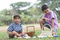 Two cute little Caucasian and Asian child boy hunting Easter eggs. kids collecting eggs in basket, counting eggs after play game Royalty Free Stock Photo