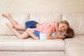 Two cute little Caucasian girls siblings playing at home. Adorable children kids lying hugging on a couch together. Authentic Royalty Free Stock Photo