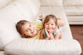 Two cute little Caucasian girls siblings playing at home. Adorable smiling children kids lying on a couch together. Authentic Royalty Free Stock Photo