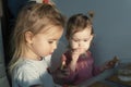 Two cute little caucasian girls sitting at the table, eating, looking. Royalty Free Stock Photo