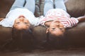 Two cute little child girls are lying on their backs on sofa