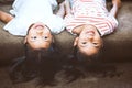 Two cute little child girls are lying on their backs on sofa